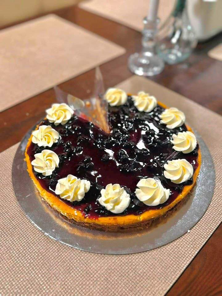 A whole blueberry cheesecake piped with cream