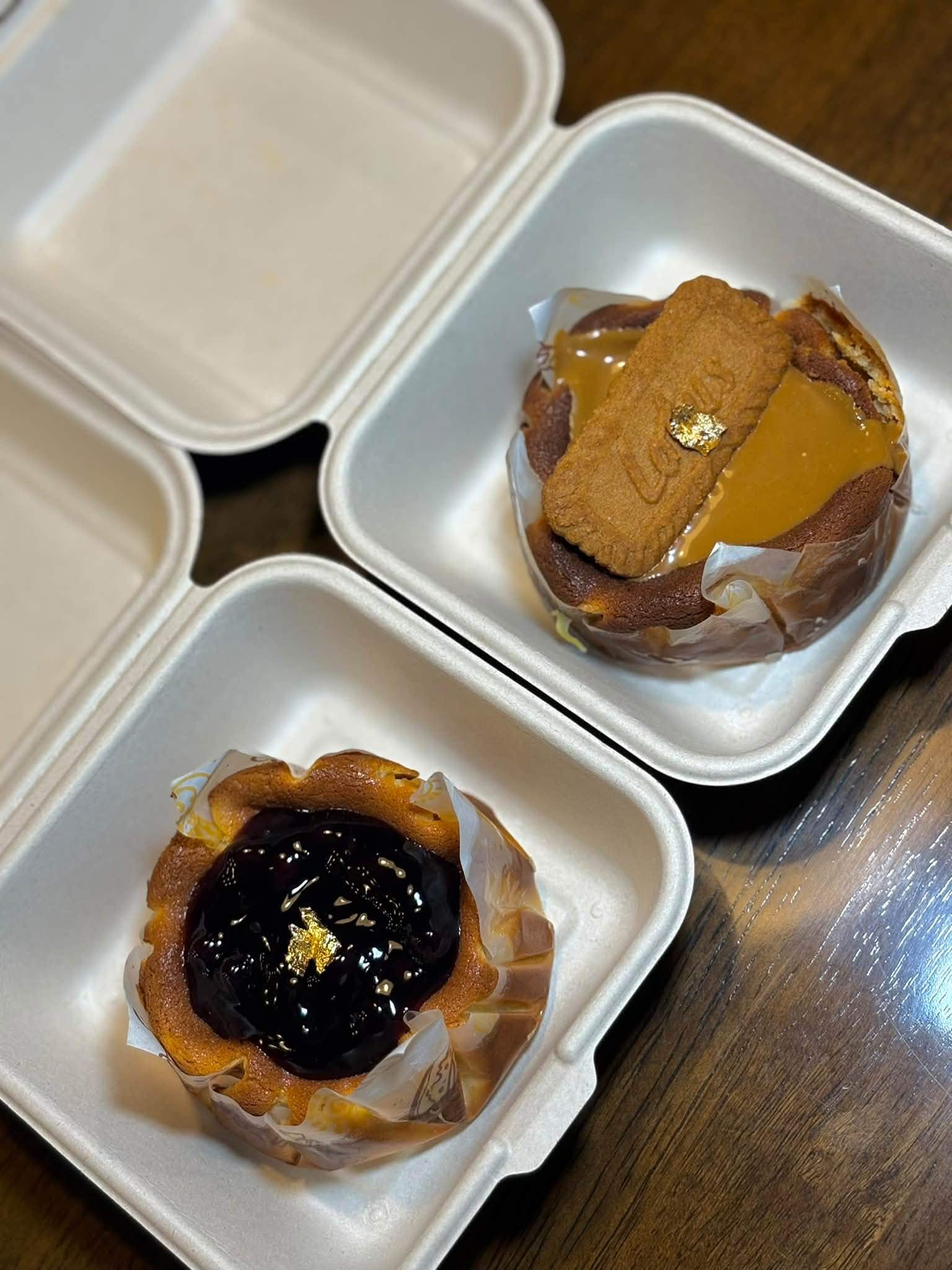 Two baked tarts, one topped with biscuit and caramel and one with blueberry
