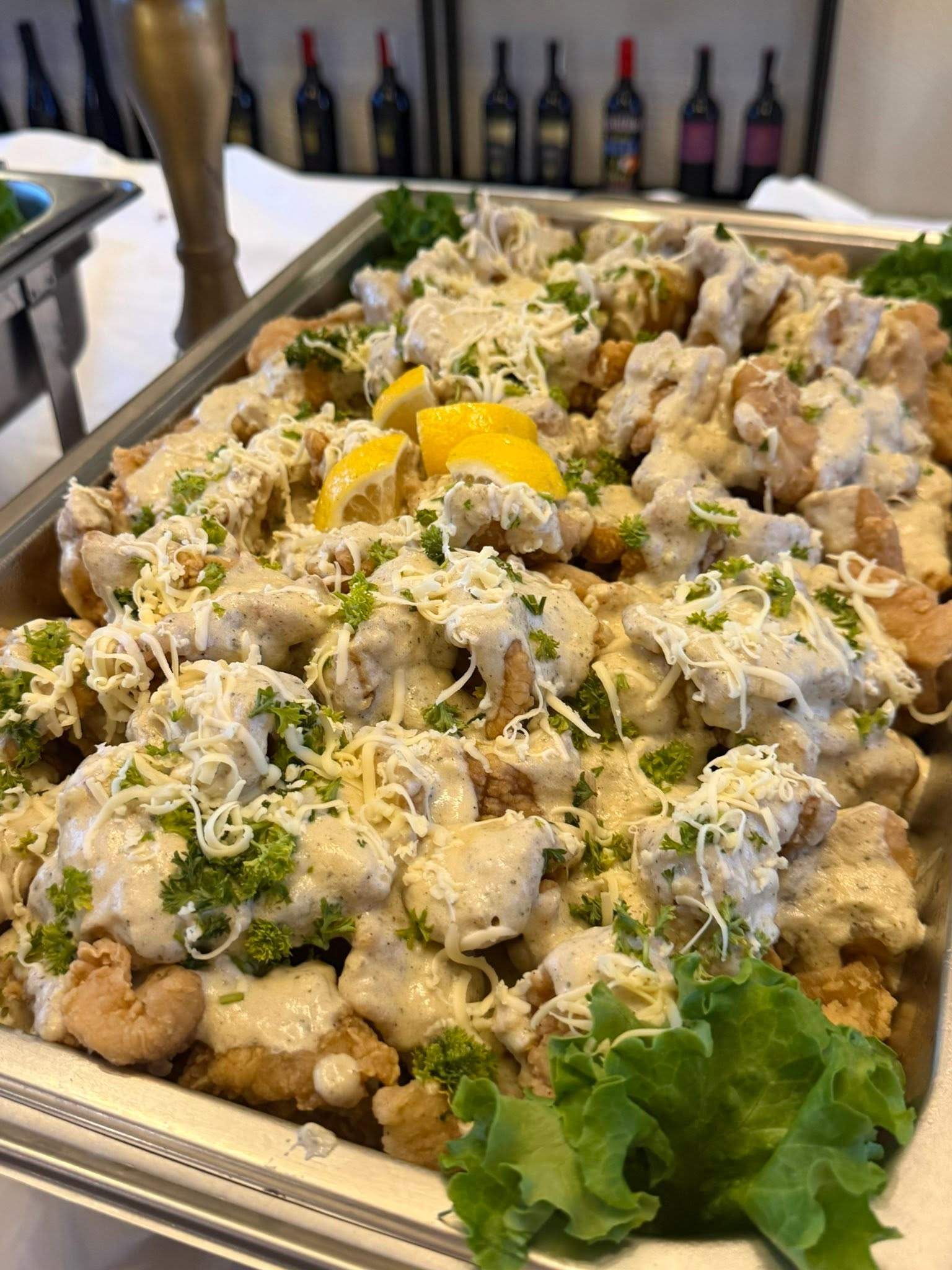 A tray of a creamy dish topped with grated cheese and greens