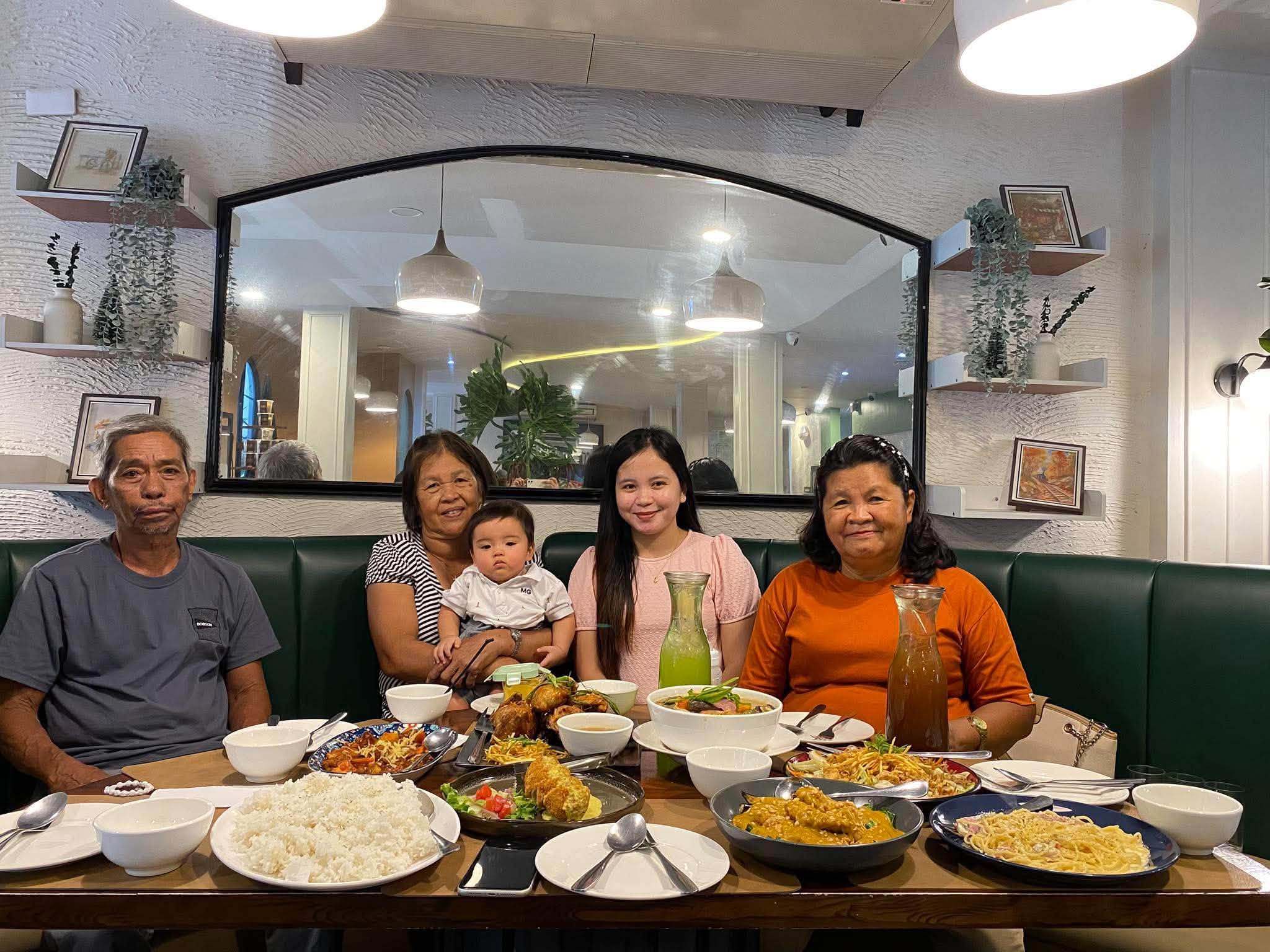 A family sharing a meal at a long table in the green-banquette dining room