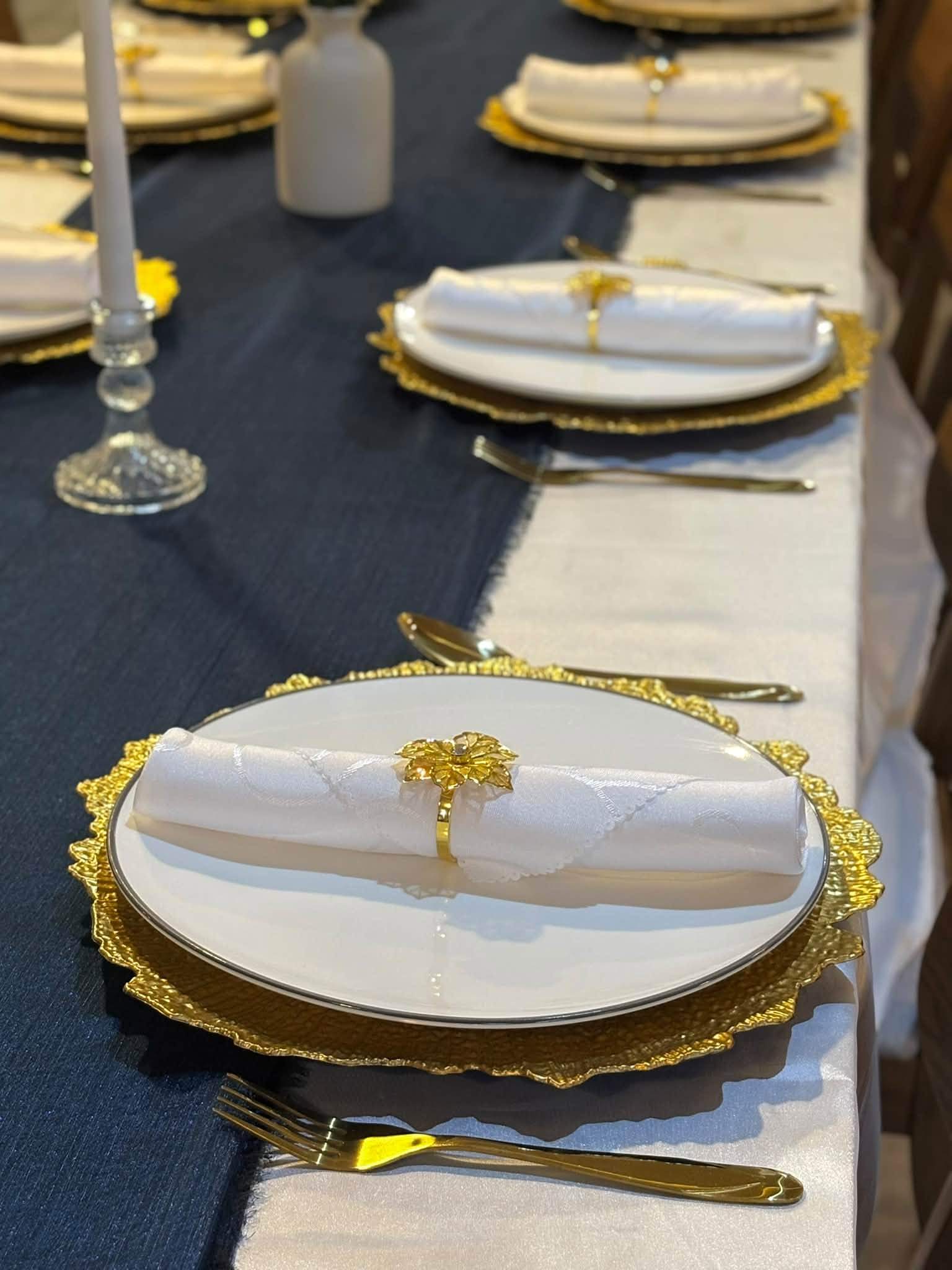 Navy table runner with a gold charger, white napkin and gold cutlery
