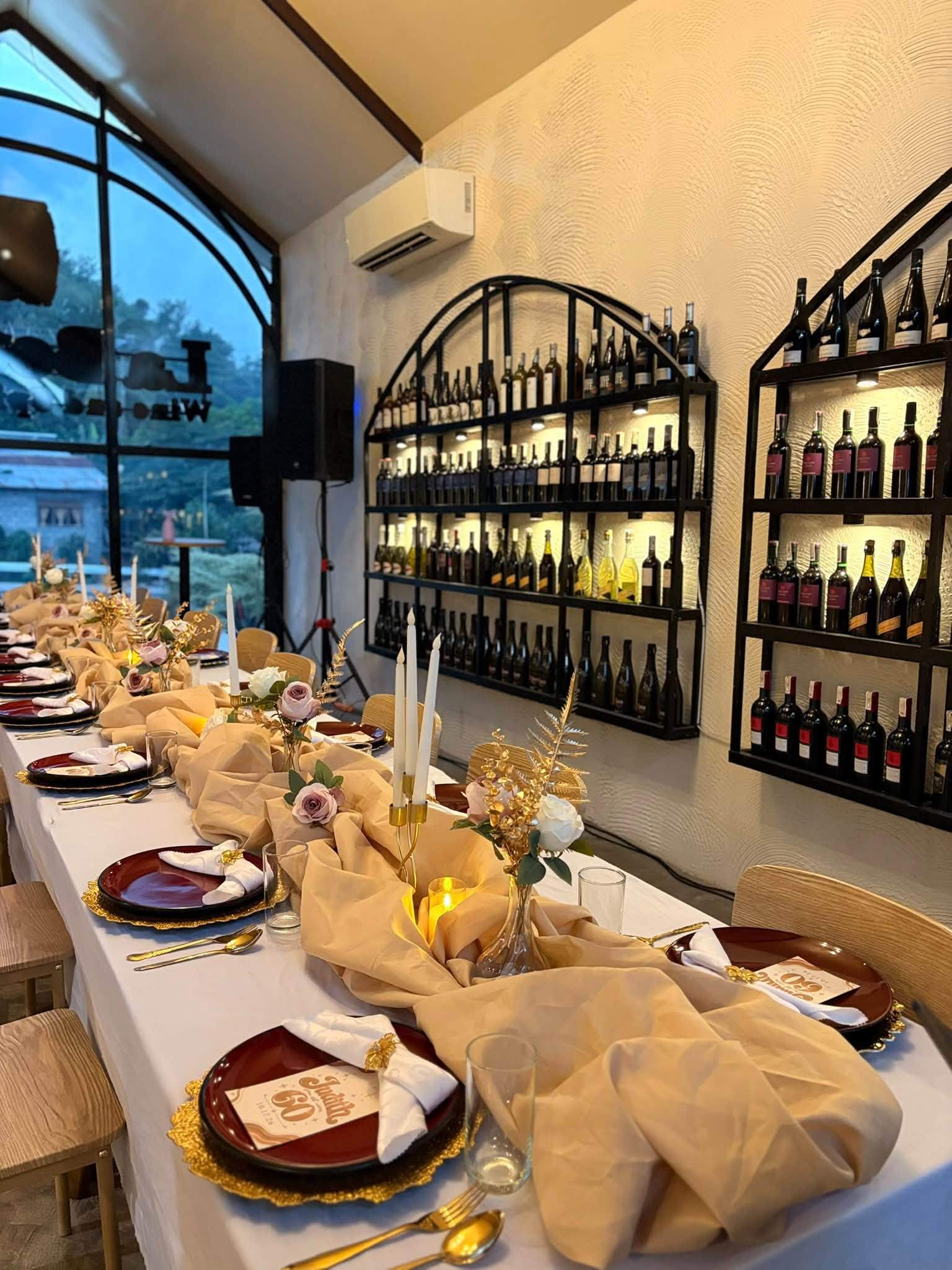 A long celebration table with champagne-coloured runners under the arched window and wine wall