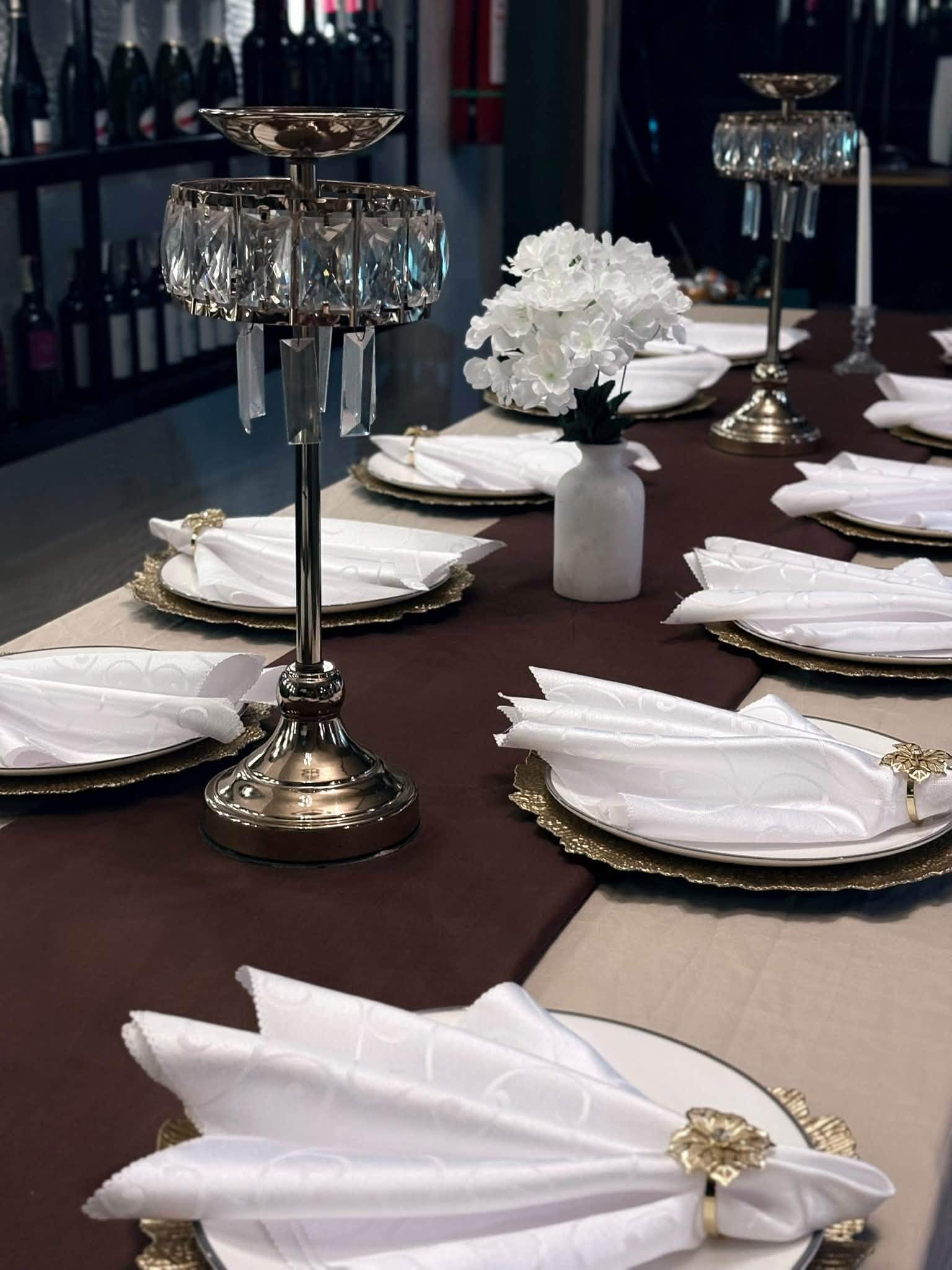 Crystal candelabra and folded white napkins on a table with a brown runner